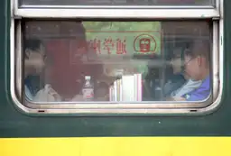 Voyager en train en Chine – Passagers assis à bord d'un train traditionnel chinois vus de l'extérieur par la fenêtre.