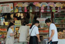 Famille devant une échoppe locale colorée en Chine vendant des souvenirs et des rafraîchissements.