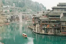 Que regarder avant de partir en Chine – Village traditionnel au bord de l'eau avec maisons sur pilotis et ponts en pierre.