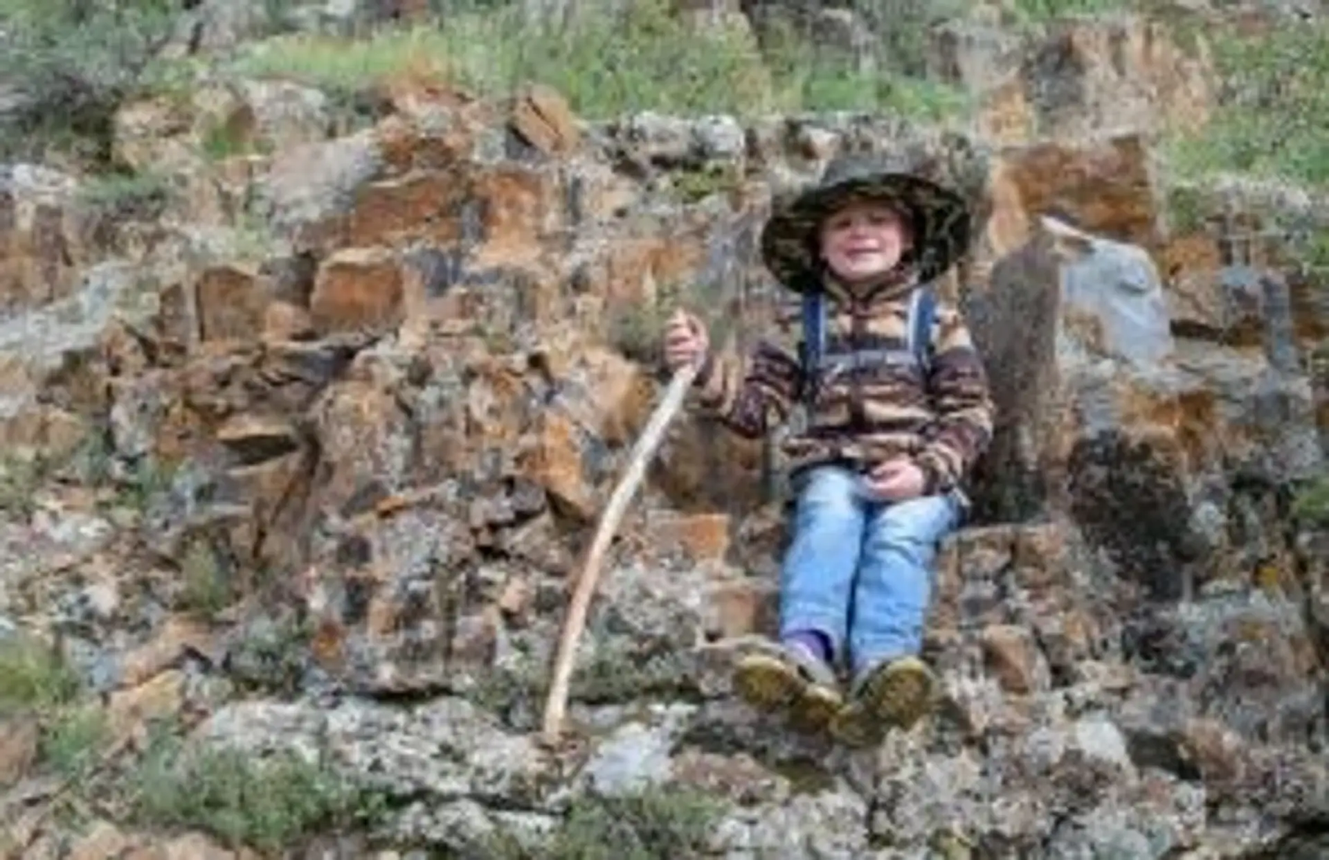 Jeune enfant arménien souriant assis sur des rochers dans les montagnes d'Arménie
