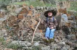Jeune enfant arménien souriant assis sur des rochers dans les montagnes d'Arménie