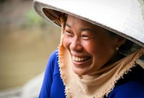 Travel in Asia - A Vietnamese woman wearing a traditional non la hat smiling broadly