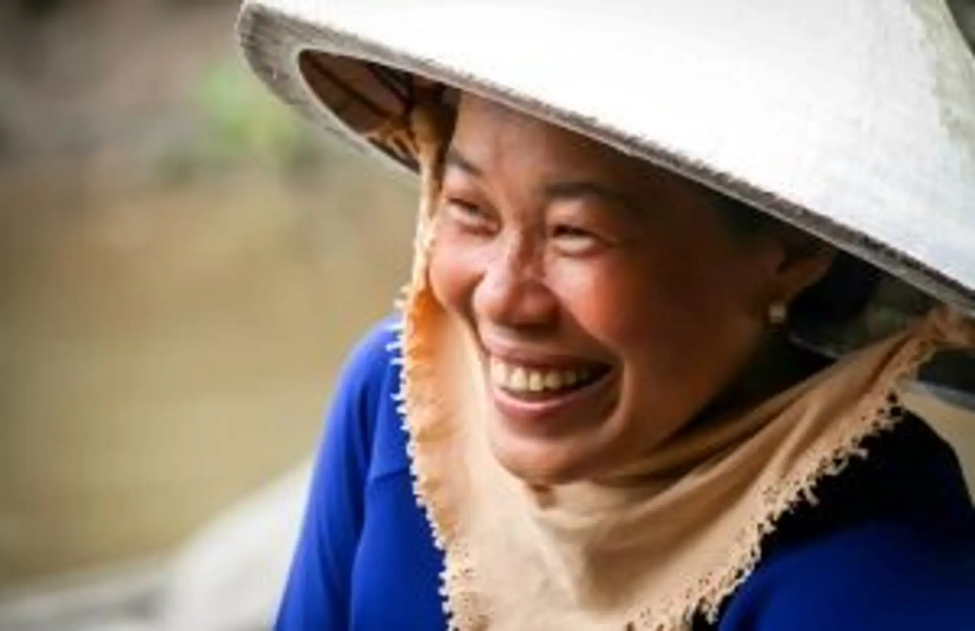Travel in Asia - A Vietnamese woman wearing a traditional non la hat smiling broadly