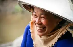 Travel in Asia - A Vietnamese woman wearing a traditional non la hat smiling broadly