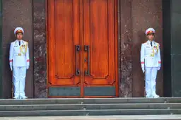 Travel in Asia - Two soldiers in white uniforms guard a wooden door outside the Ho Chi Minh Mausoleum in Hanoi, Vietnam