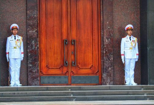 Travel in Asia - Two soldiers in white uniforms guard a wooden door outside the Ho Chi Minh Mausoleum in Hanoi, Vietnam