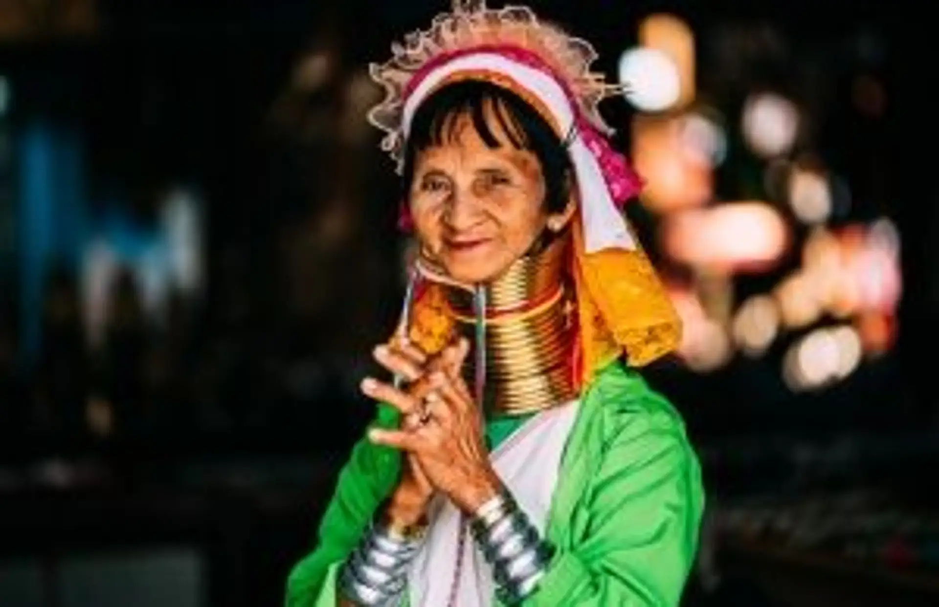 Portrait d'un homme thaïlandais en chapeau traditionnel devant un paysage de montagnes verdoyantes en Thaïlande.