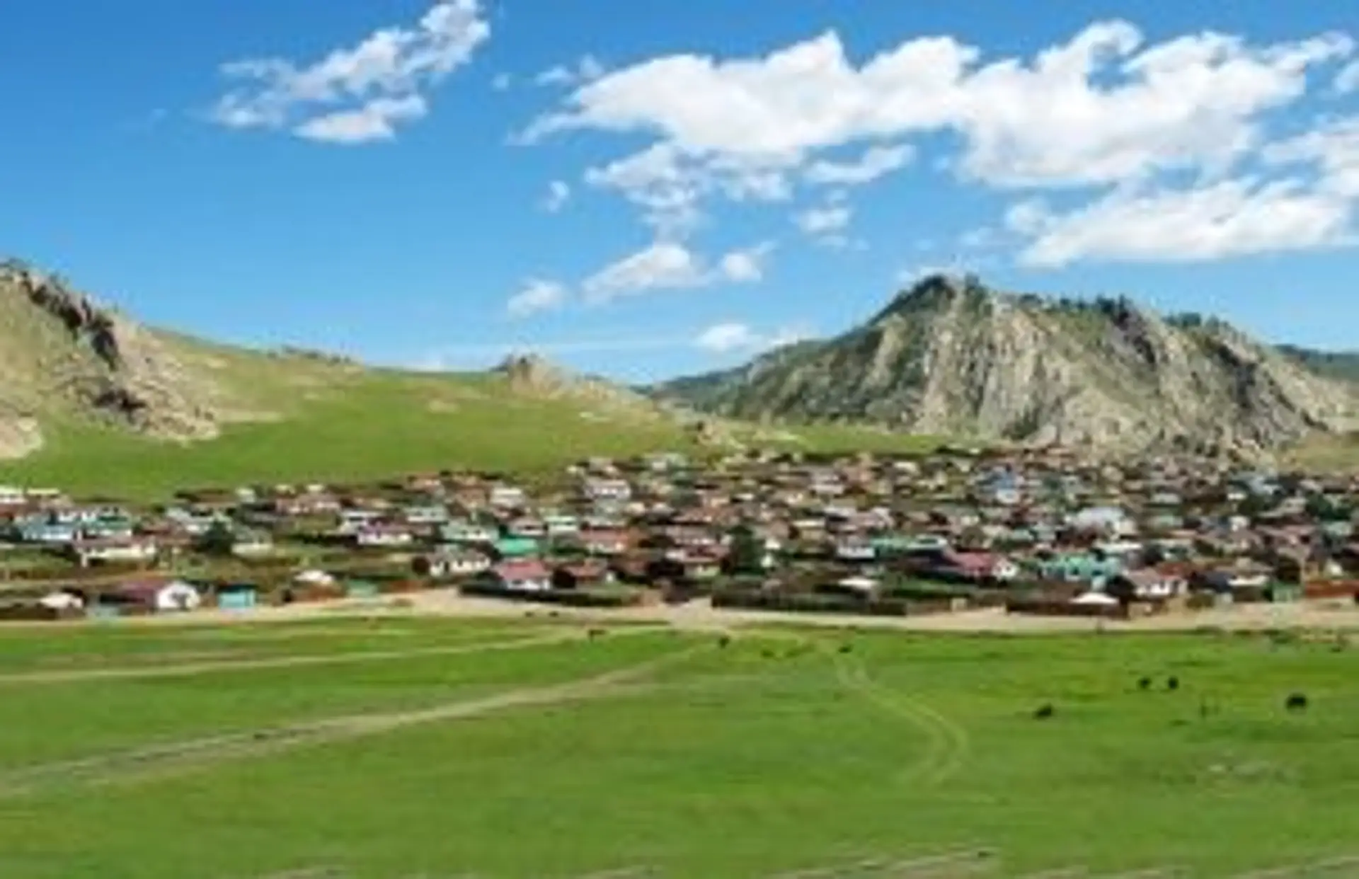 Village de yourtes et maisons traditionnelles au pied des montagnes sous un ciel de Mongolie