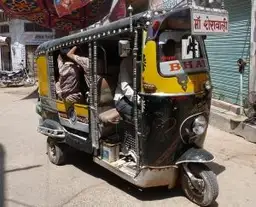 Travel in Asia - An auto rickshaw with driver and passengers aboard on a city street in India