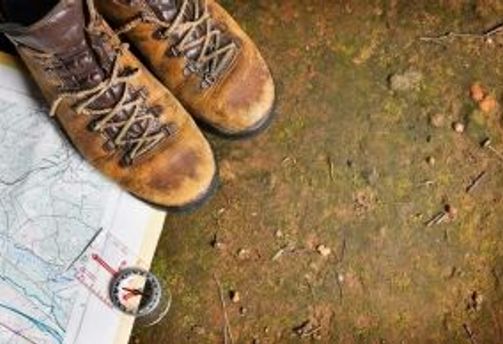 Travel in Asia - A pair of hiking boots, a map, and a compass on the ground