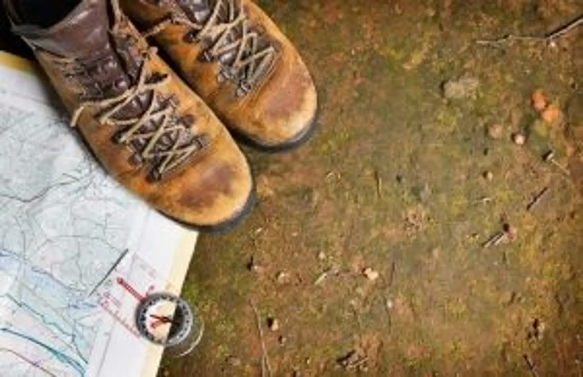 Travel in Asia - A pair of hiking boots, a map, and a compass on the ground