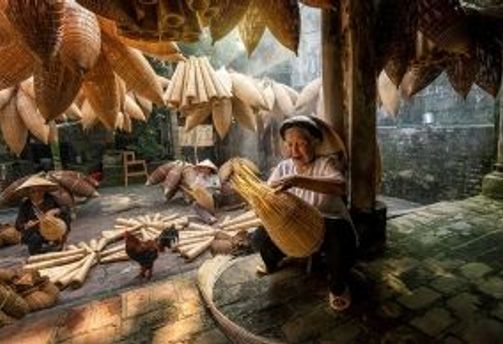 Travel Asia - A person weaving a fish trap indoors in Vietnam