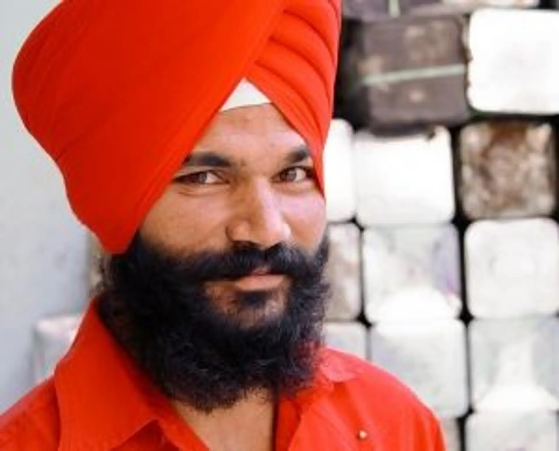 Travel in Asia - Bearded Indian man with red turban and red shirt smiling