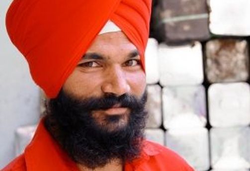 Travel in Asia - Bearded Indian man with red turban and red shirt smiling