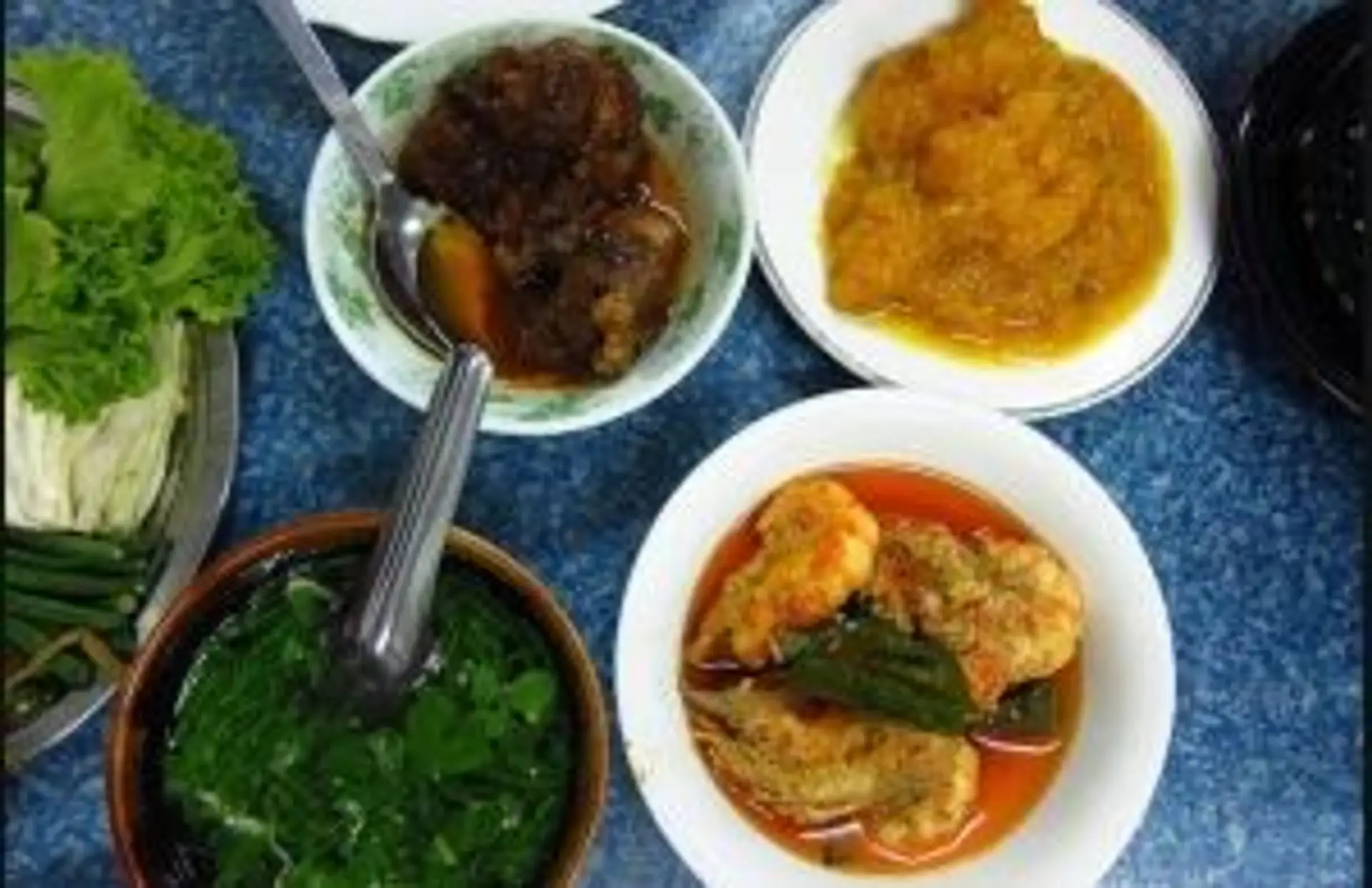 Assortiment de plats traditionnels birmans servis dans des bols, illustrant la diversité de la nourriture en Birmanie.