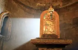 Faisceau de lumière naturelle éclairant un autel en pierre dans un monastère médiéval en Arménie.