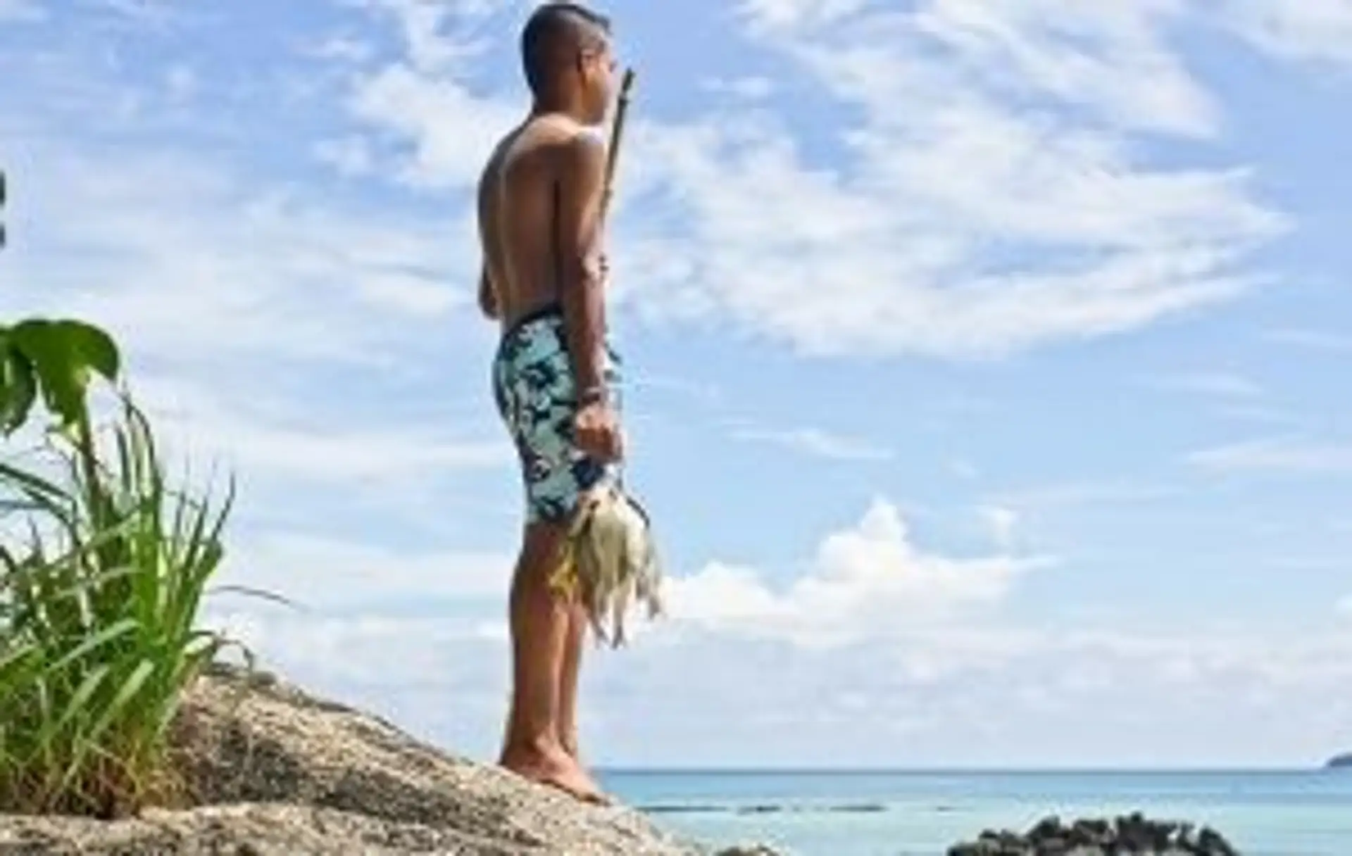 Jeune homme contemplant la mer depuis un rocher, illustrant la sérénité et la sécurité d'un voyage en Thaïlande.