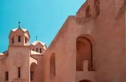 Façade en pierre ocre d'une église apostolique arménienne sous un ciel bleu pur, témoignant du patrimoine chrétien du pays.