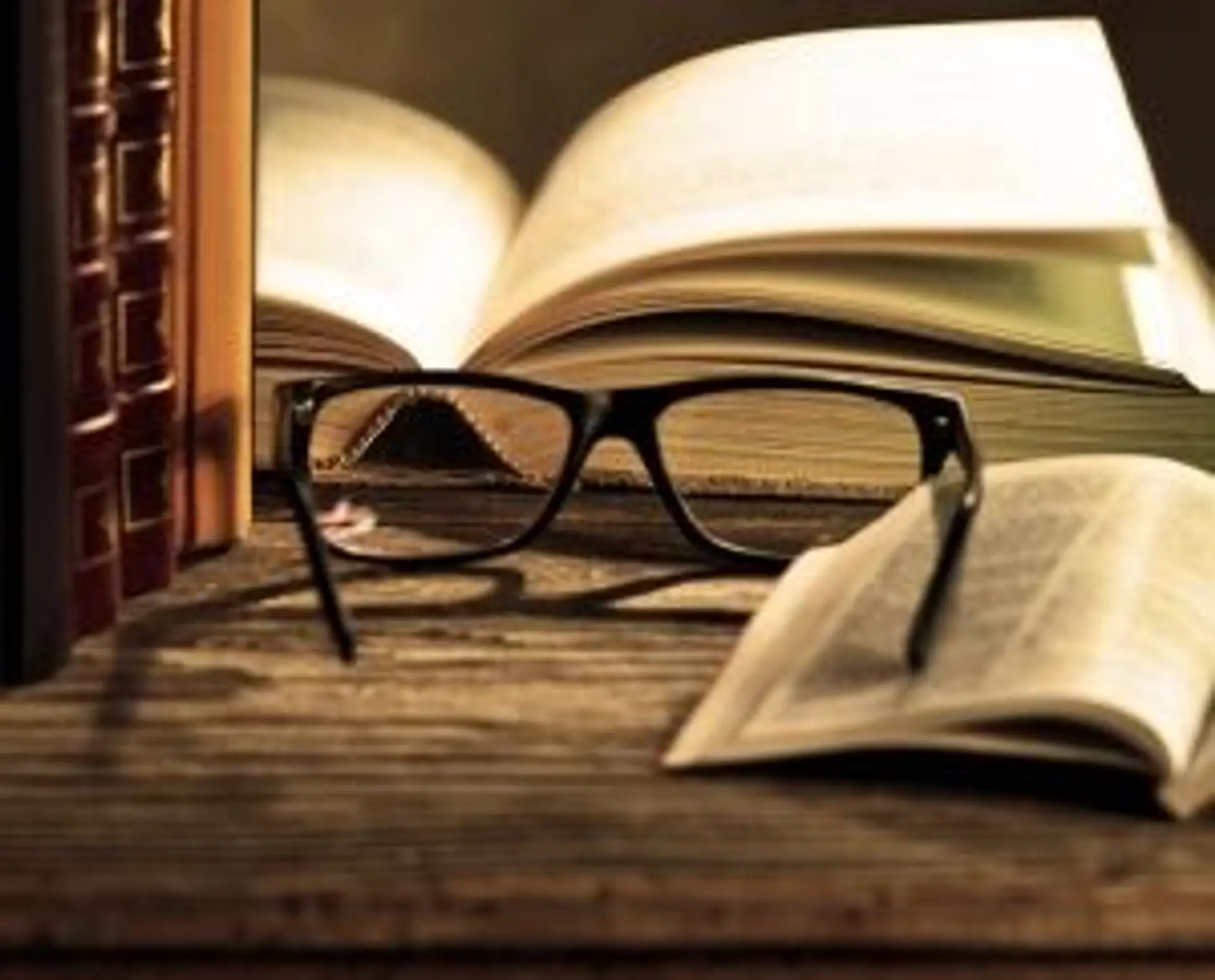 Une paire de lunettes posée sur des livres ouverts sur une table en bois