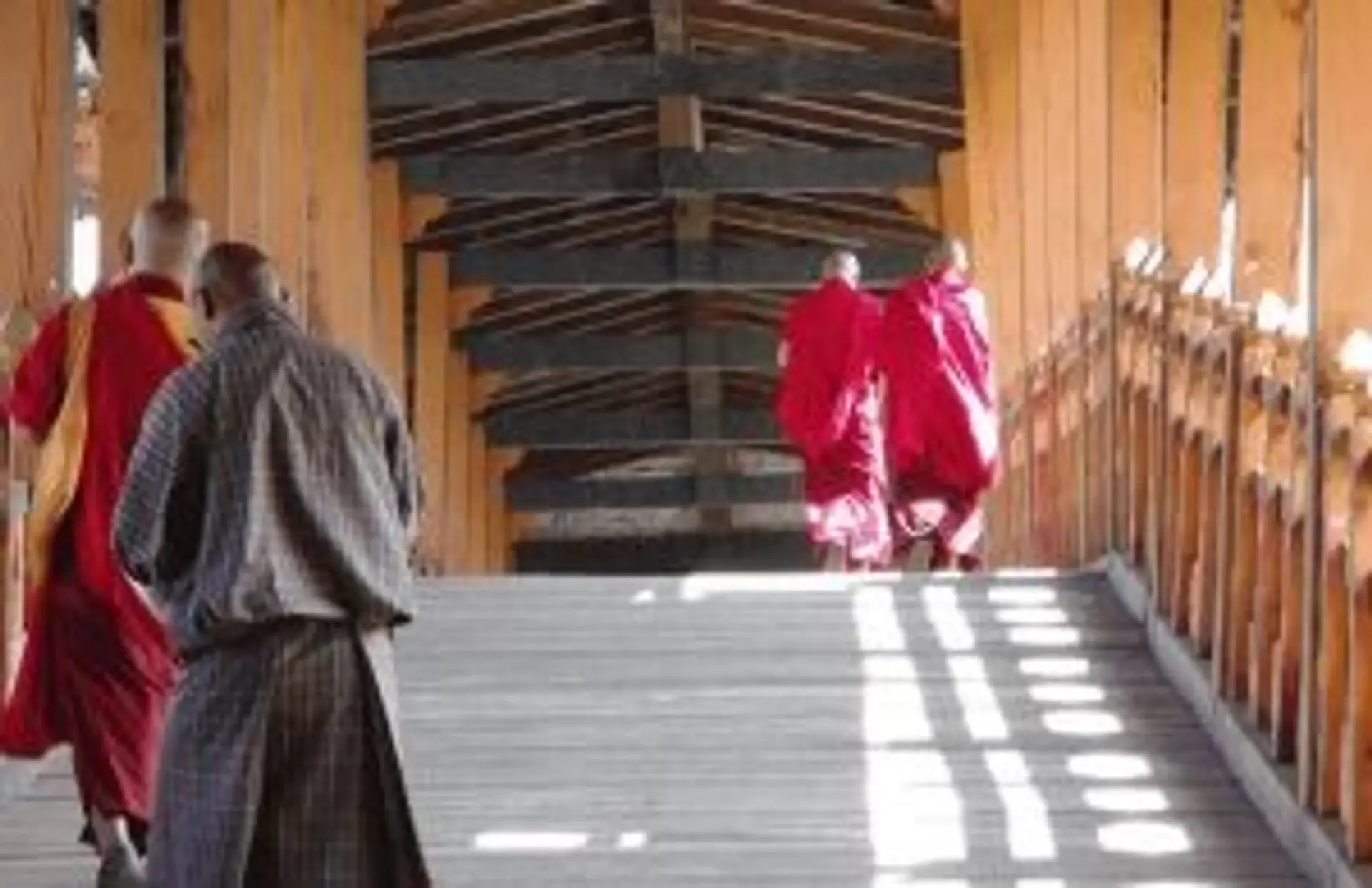 Moines en robes rouges marchant dans une galerie traditionnelle d'un Dzong au Bhoutan