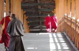 Moines en robes rouges marchant dans une galerie traditionnelle d'un Dzong au Bhoutan