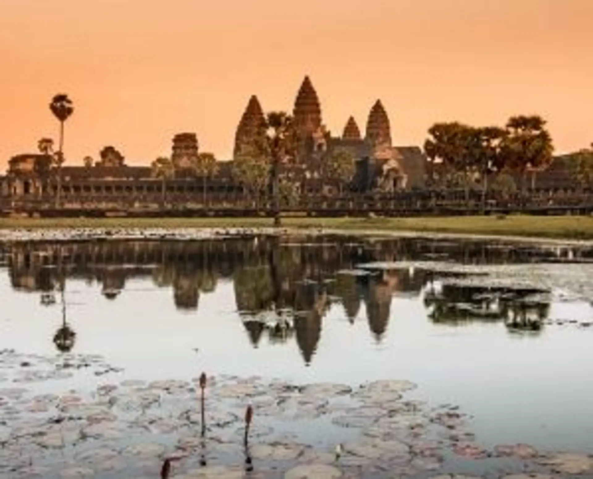 Silhouette des tours du temple d'Angkor Wat se reflétant dans l'eau au lever du soleil au Cambodge