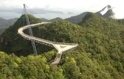 Voyage en Malaisie — Le pont suspendu incurvé Langkawi Sky Bridge surplombant la jungle luxuriante sous la brume.