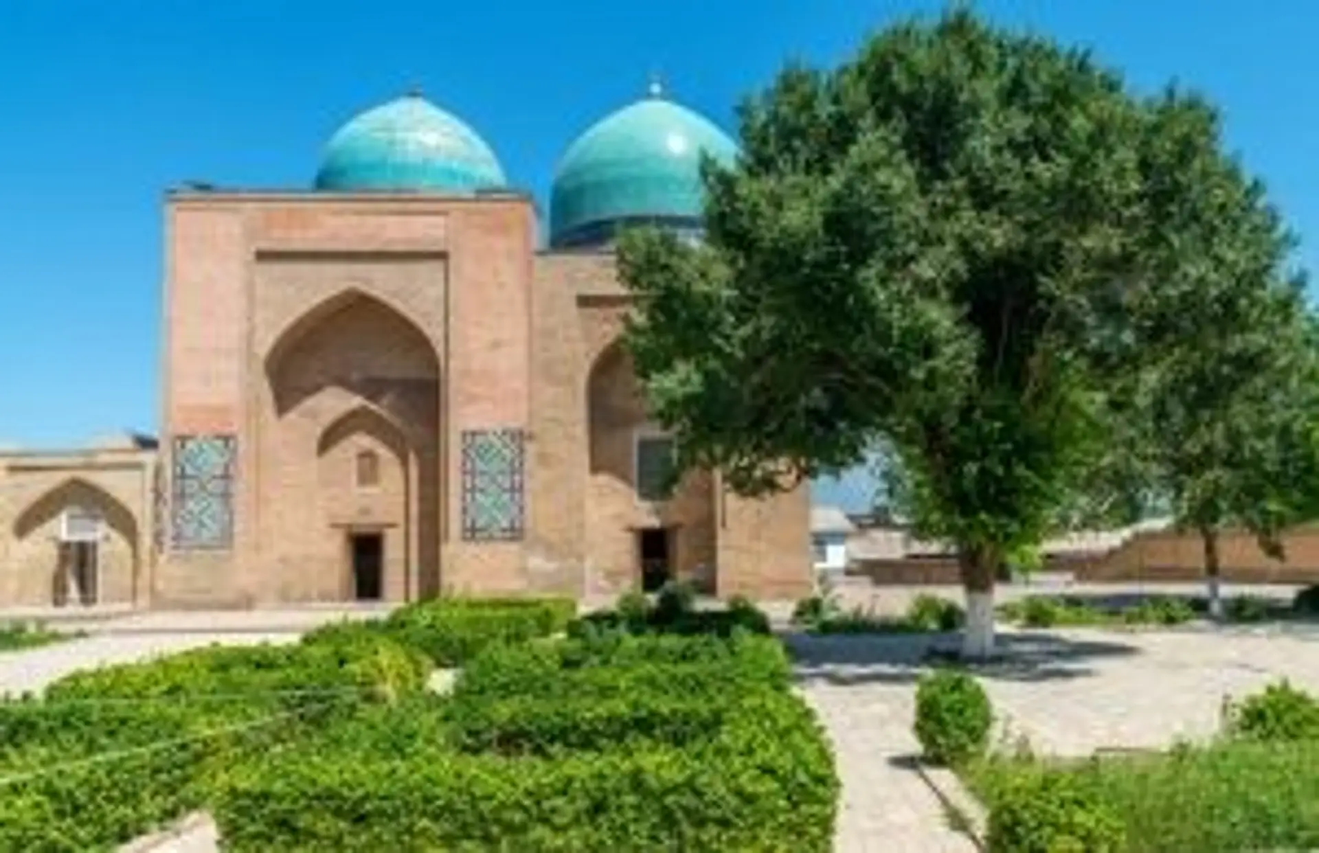Voyage en Ouzbékistan - Vue sur les madrasas aux dômes bleus de la place du Régistan à Samarcande au coucher du soleil.