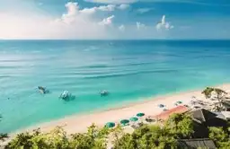 Vue aérienne d'une plage de sable blanc et eau turquoise avec parasols à Bali
