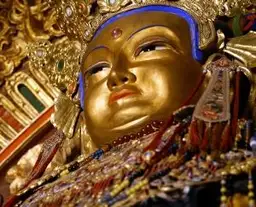 Statue dorée de divinité bouddhiste ornée de bijoux traditionnels dans un monastère en Mongolie.