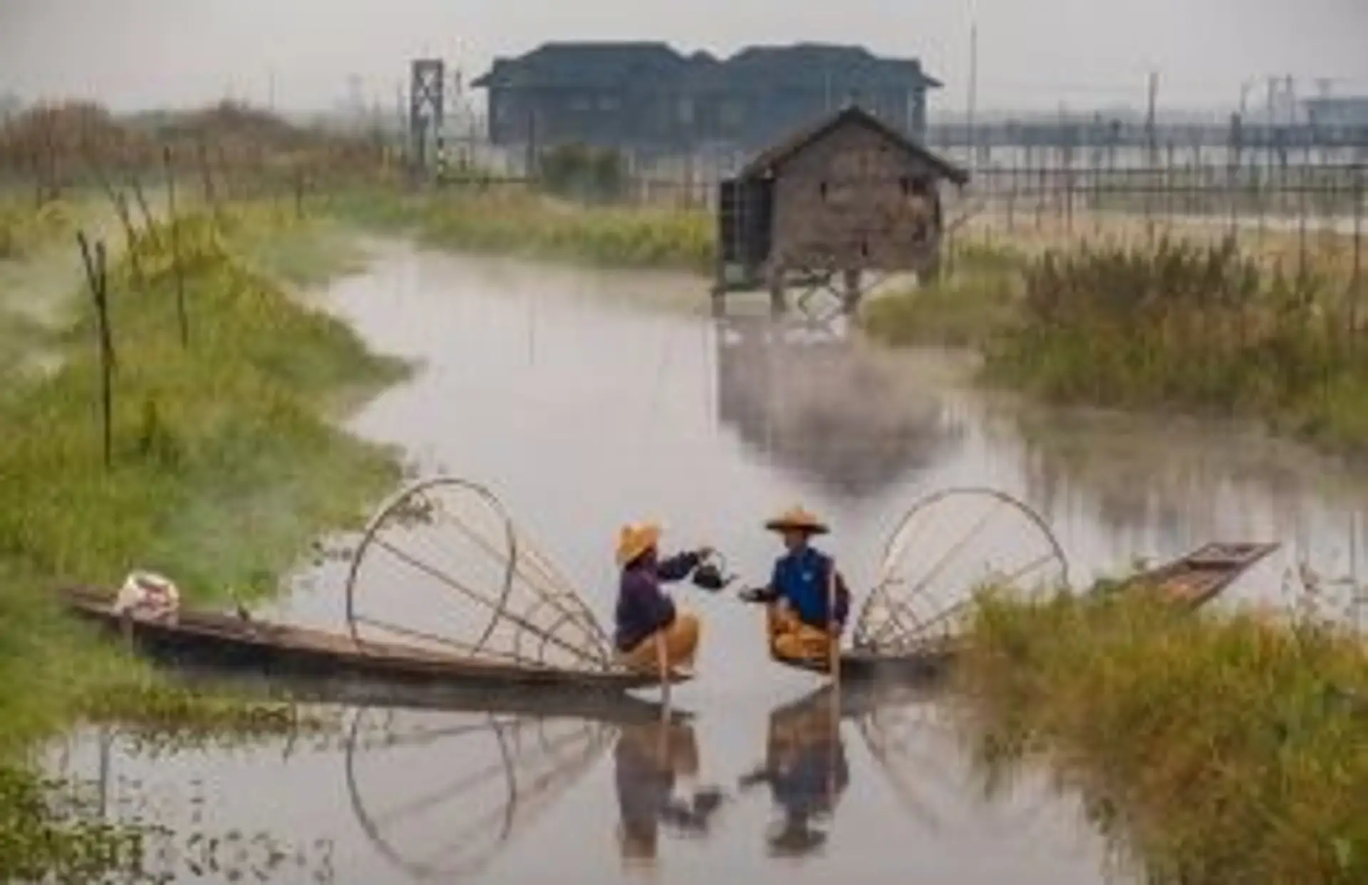 Deux pêcheurs sur leurs barques traditionnelles naviguant au milieu des jardins flottants sur le lac Inle en Birmanie.