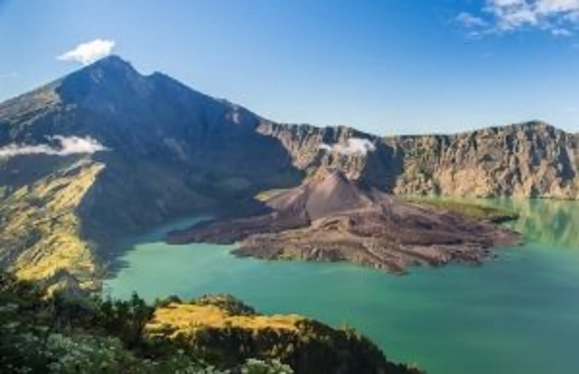 Vue panoramique du volcan Rinjani avec son lac de cratère Segara Anak sous un ciel bleu