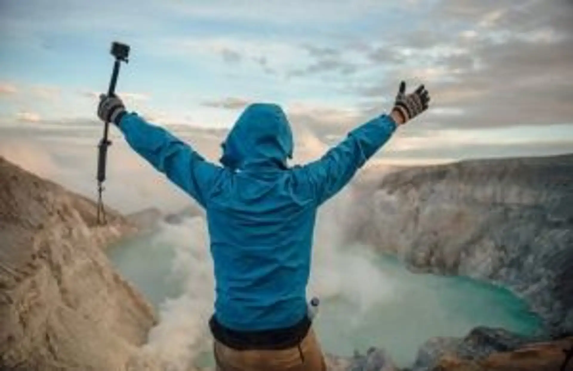 Volcans en Indonésie : randonneur face au cratère du Kawah Ijen et son lac d'acide turquoise à Java.