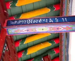 Détail d'une poutre en bois peinte avec des motifs colorés et des inscriptions en écriture mongole traditionnelle.