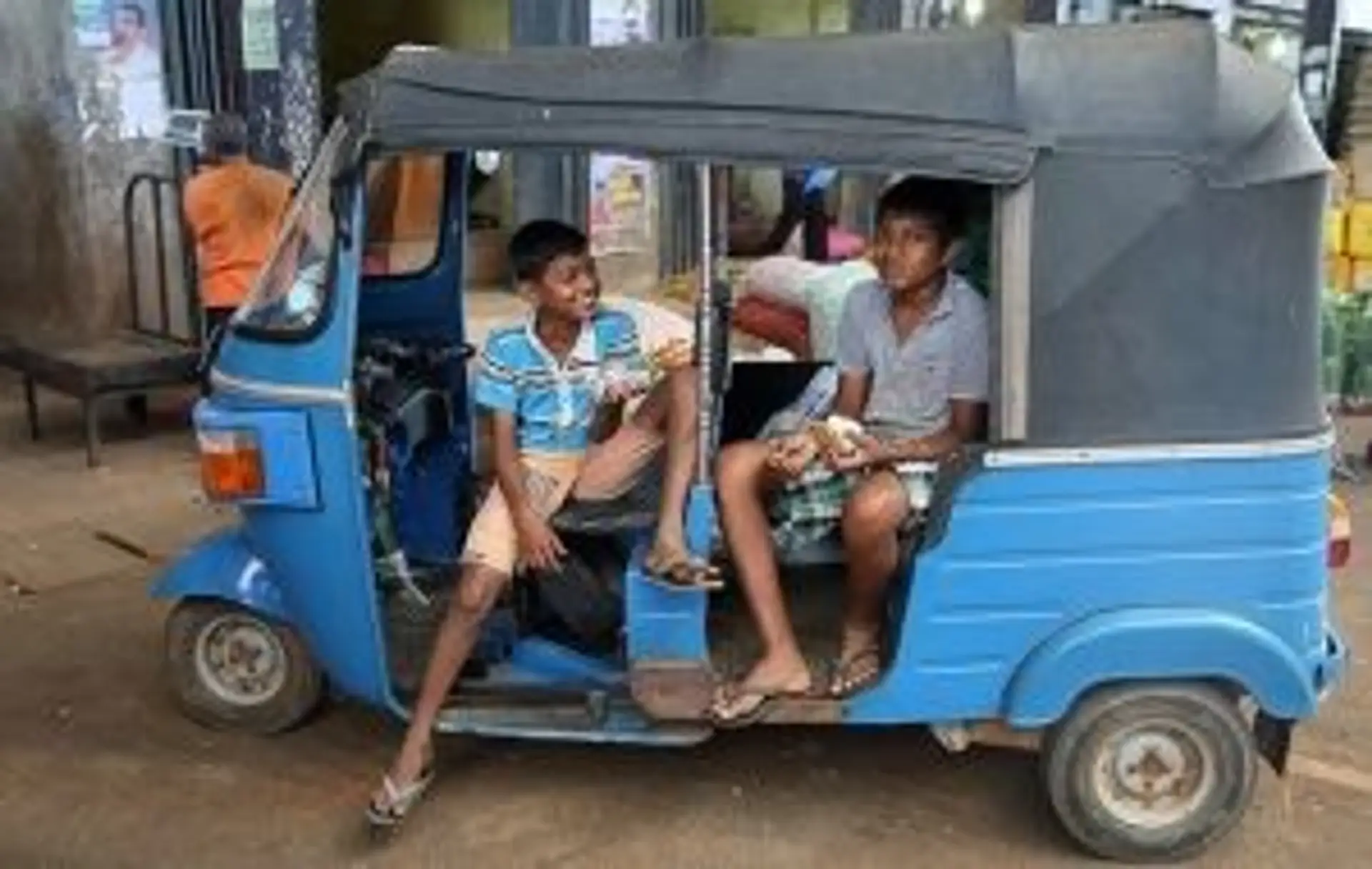 Deux jeunes hommes sri lankais discutant dans un tuk-tuk bleu traditionnel au Sri Lanka