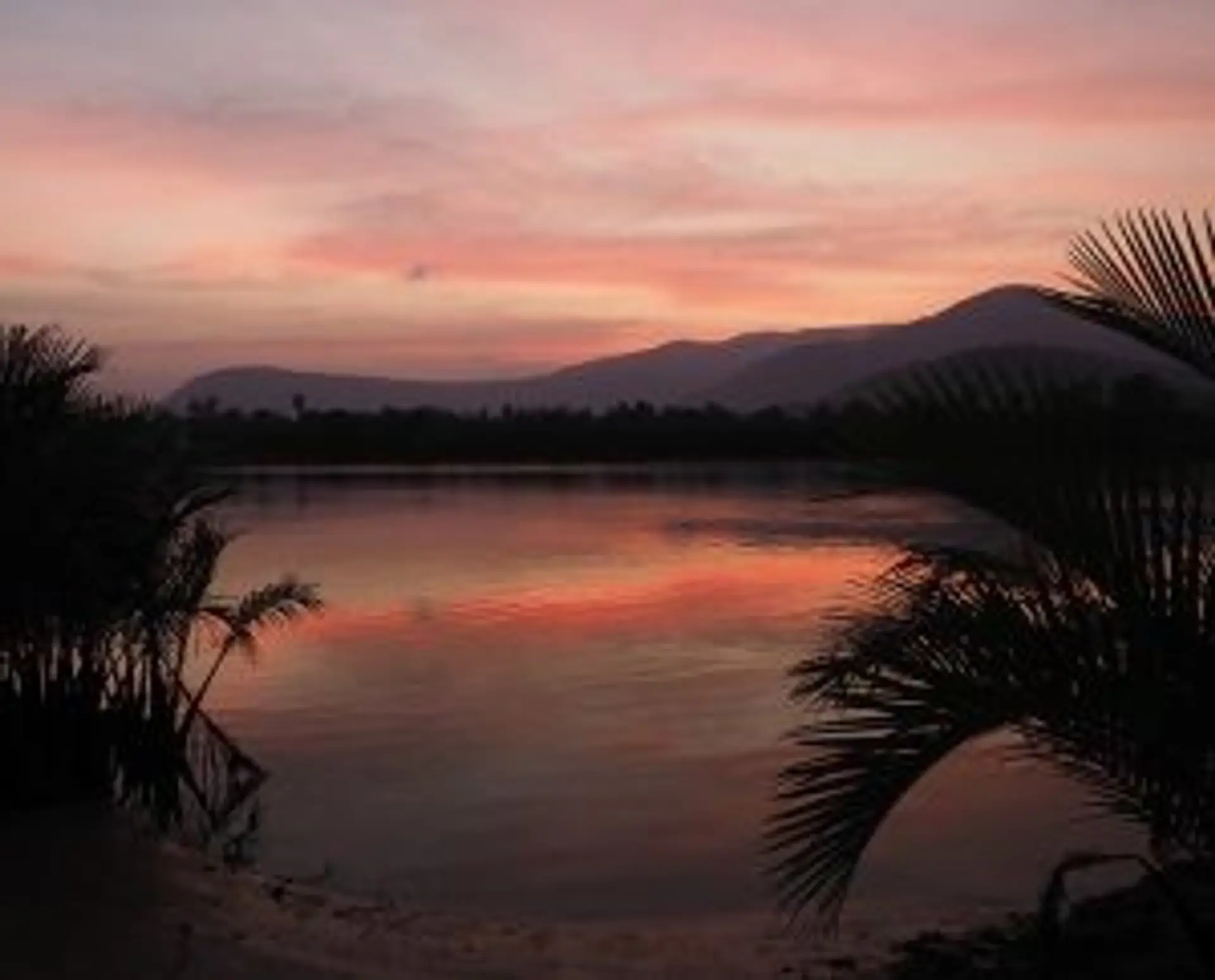 Deux enfants souriants sous la pluie tropicale dans un village rural au Cambodge pendant la mousson.