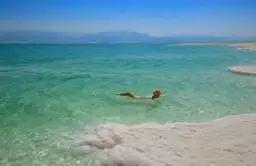Voyage en Jordanie — Femme se baignant dans les eaux turquoise et les formations de sel de la mer Morte.