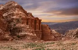 Voyage en Jordanie — Façade monumentale du Monastère Al-Deir sculptée dans la roche rose de Pétra au crépuscule.