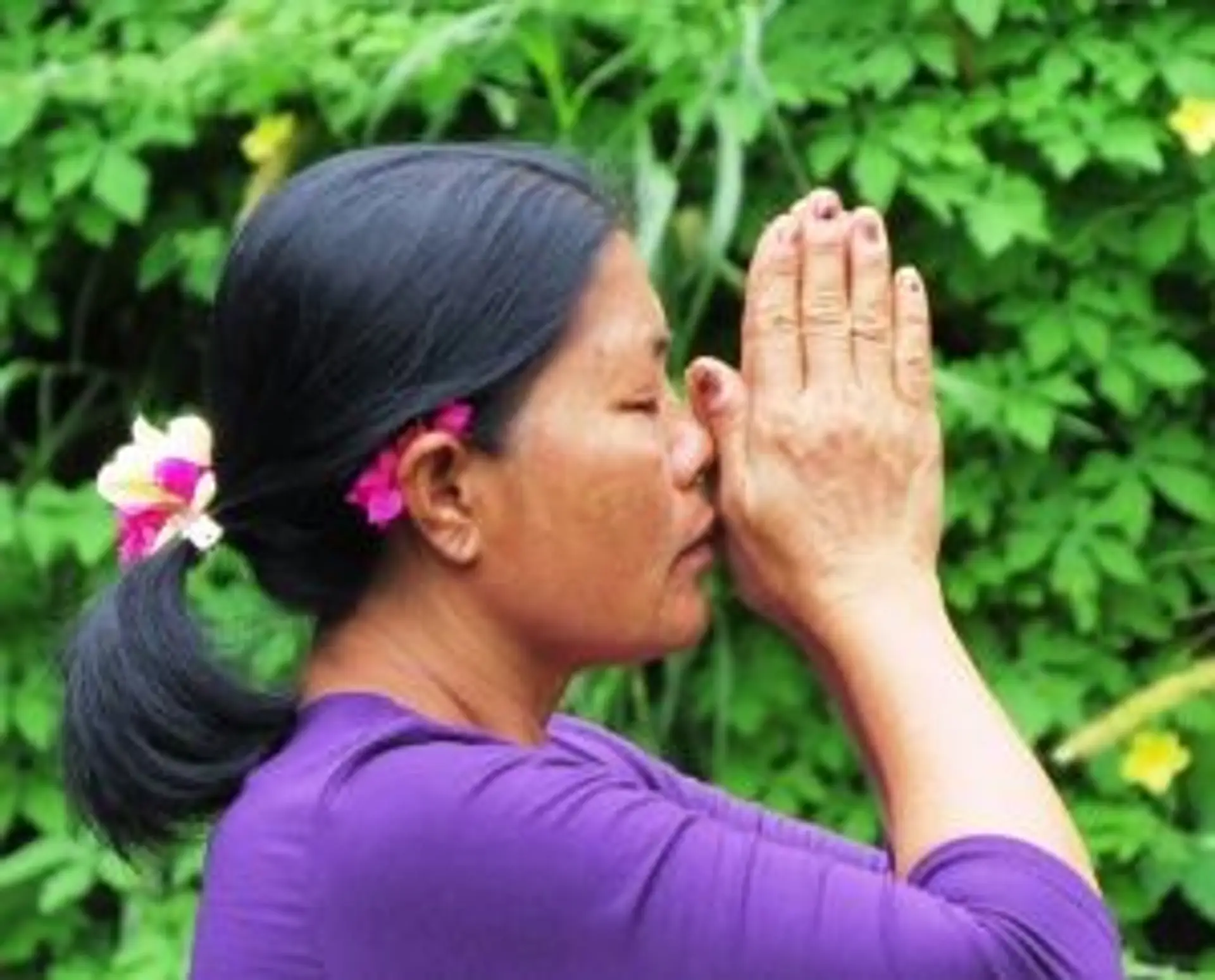 Travel in Asia - A Balinese woman praying against a leafy background