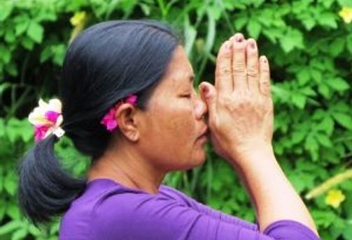 Travel in Asia - A Balinese woman praying against a leafy background