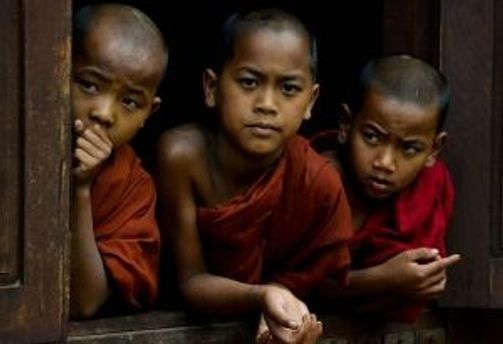 Travel in Asia - Three young, bald novice monks in a temple window.