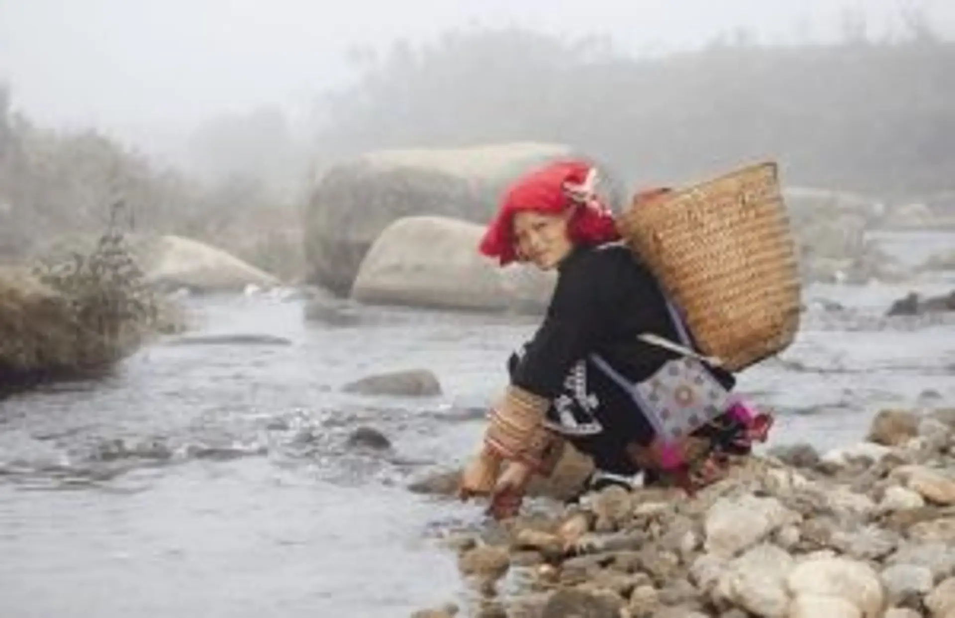 Travel in Asia - A woman of the Red Dzao ethnic group in Vietnam stooping next to a river