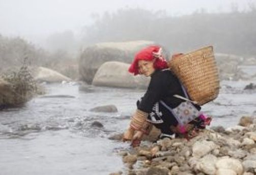 Travel in Asia - A woman of the Red Dzao ethnic group in Vietnam stooping next to a river