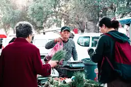 La santé en Chine – Marchand tendant un sac de produits frais sur un marché local chinois.