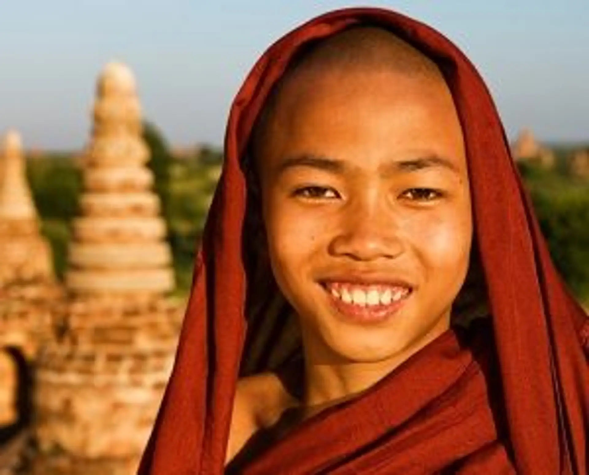 Travel in Asia - A young Buddhist monk standing in front of a stone stupa in Myanmar.