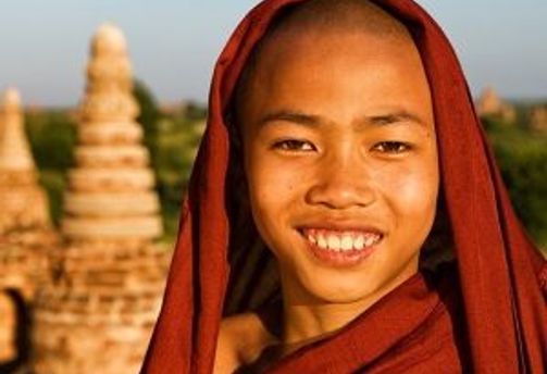 Travel in Asia - A young Buddhist monk standing in front of a stone stupa in Myanmar.