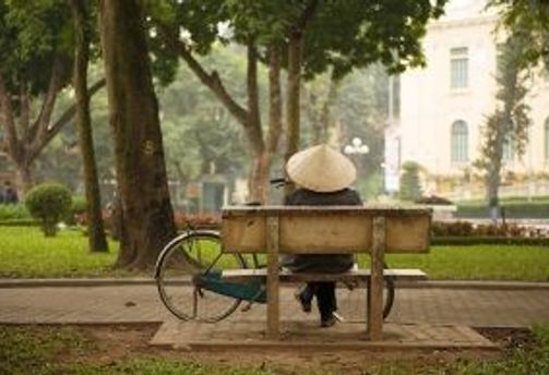 Travel in Asia - Person sitting on a bench with a bicycle nearby in a city park in Hanoi, Vietnam