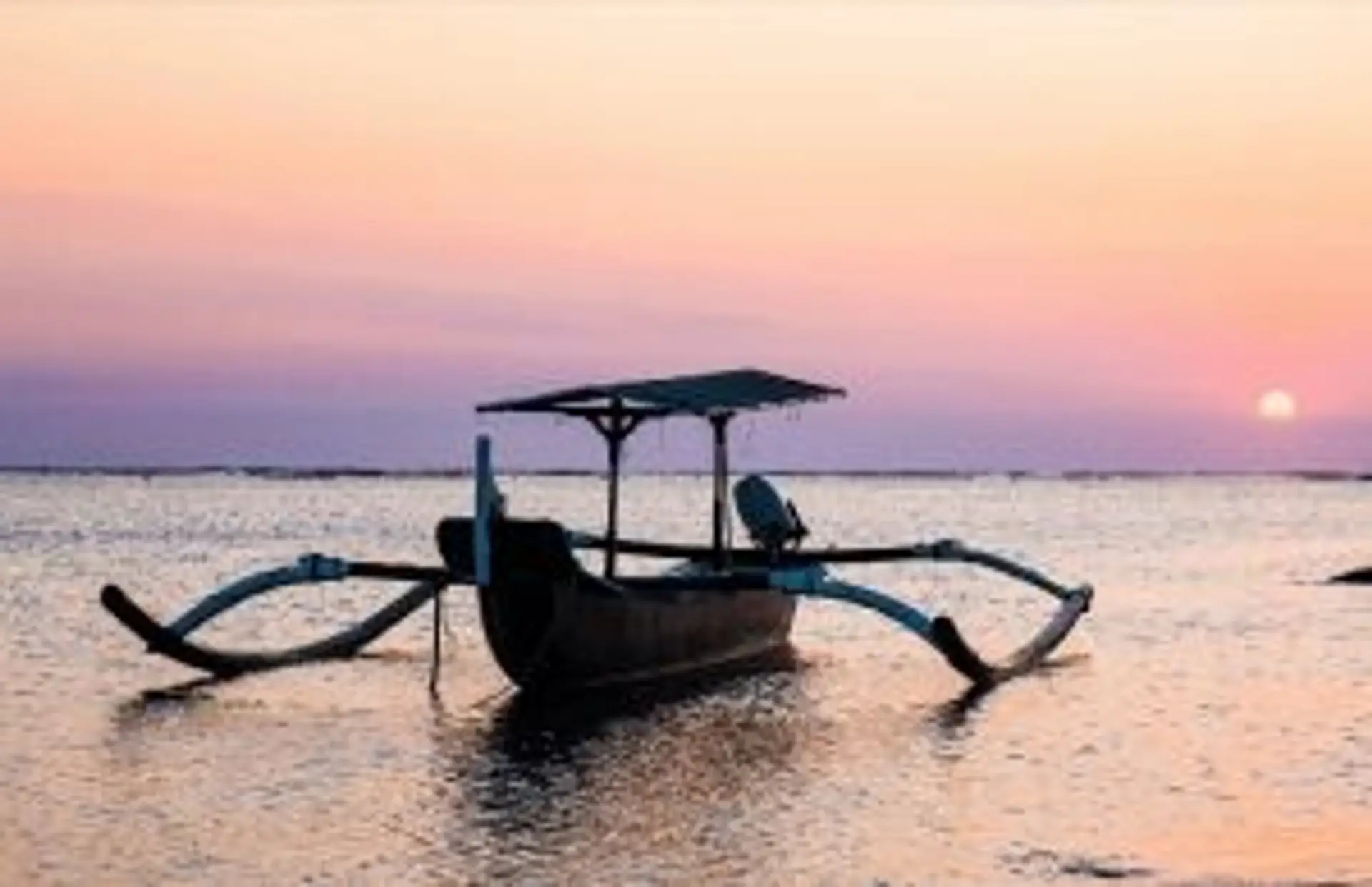 Bateau traditionnel Jukung sur une plage de Bali au coucher du soleil