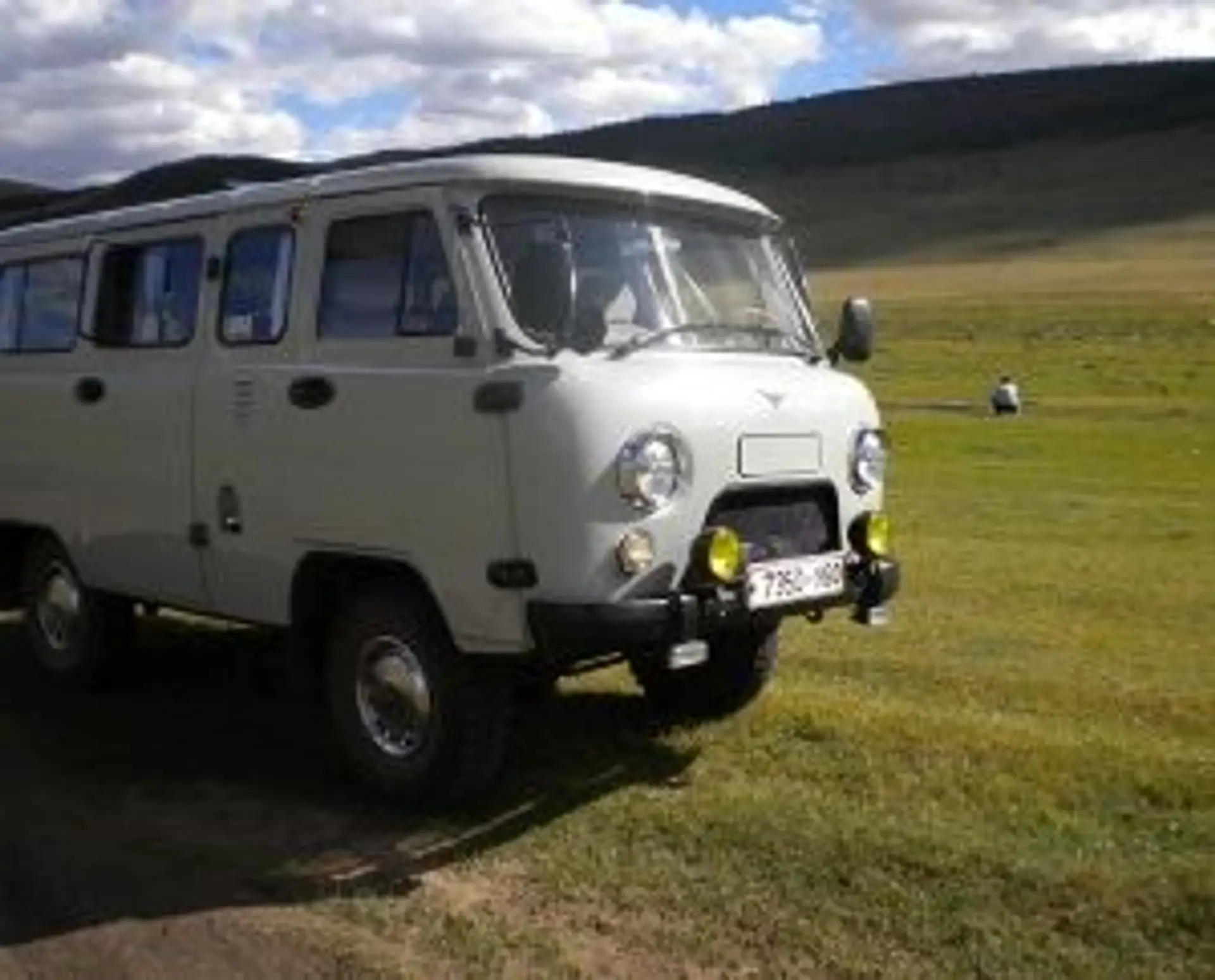 Voyage en Mongolie — Van russe blanc 4x4 UAZ stationné dans la steppe sous un ciel bleu.