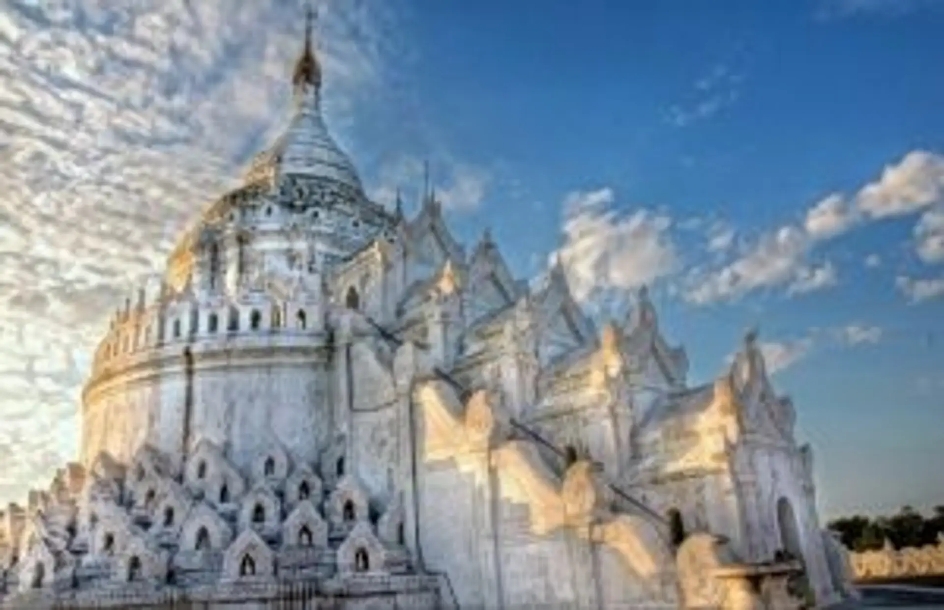Pagode Hsinbyume à Mingun, une structure circulaire blanche aux vagues architecturales sous un ciel bleu en Birmanie.